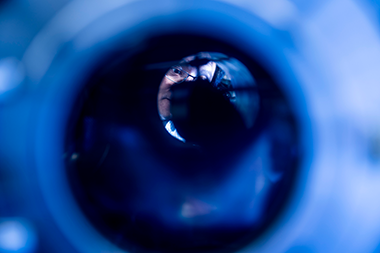 Kin Chung Fong looking into a long tube. there is a blue overtone