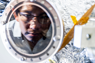 Kin Chung Fong looking through a circular mirror