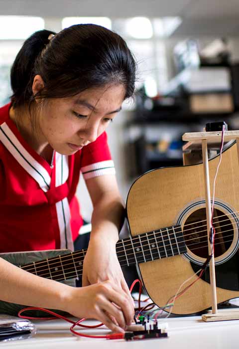student working with a guitar